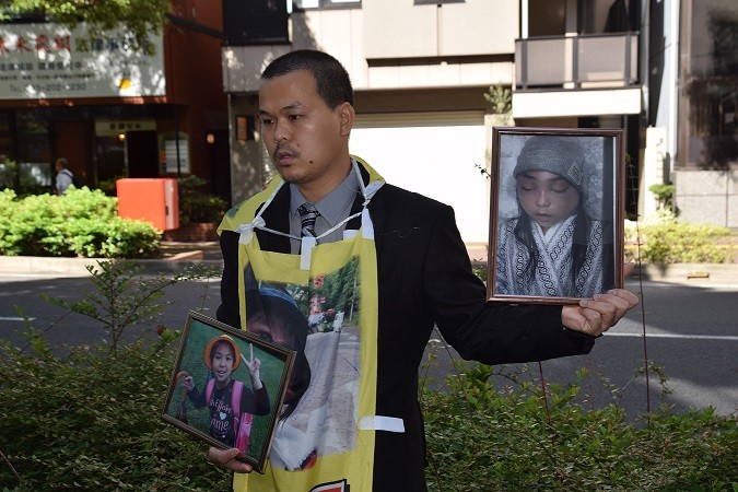 Anh Lê Anh Hào, bố của nạn nhân Nhật Linh, mang theo hai bức ảnh của con gái, một vui tươi, một khốn khổ, xuất hiện tại tòa. Ảnh: Cẩm Tuyến- Hồng Hà
