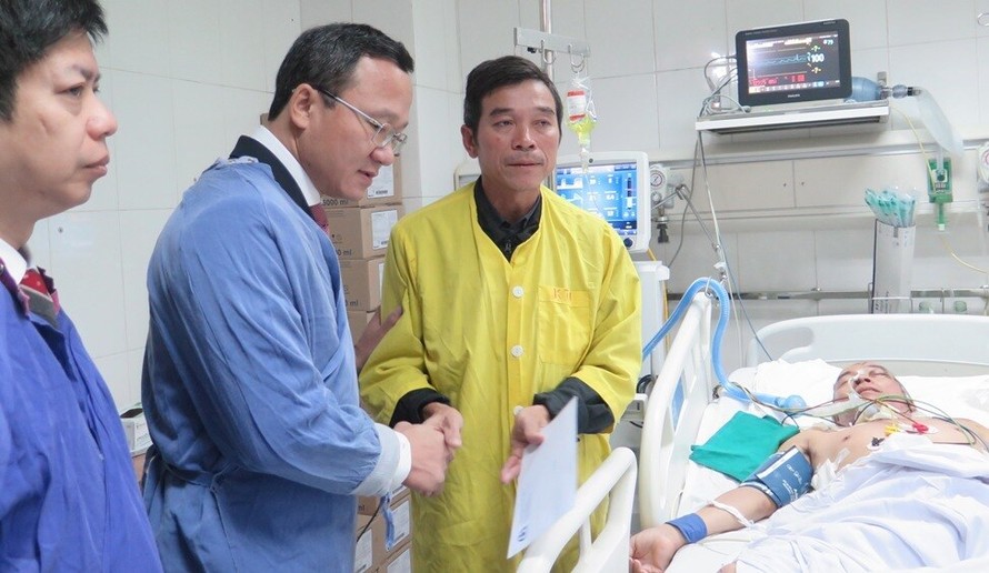 Phó Chủ tịch chuyên trách Uỷ ban ATGT Quốc gia Khuất Việt Hùng động viên bố nạn nhân Ngô Văn Tuấn đang điều trị chấn thương do tai nạn giao thông tại Bệnh viện Việt Đức. 