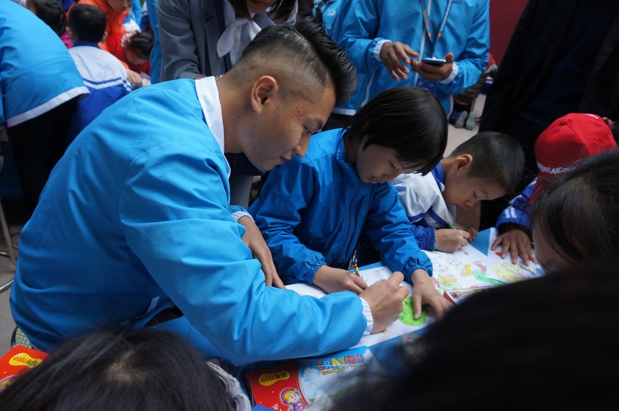 Một đại biểu thanh niên Việt Nam hướng dẫn trẻ khuyết tật tại trường Chuyên biệt Bình Minh, Đông Anh vẽ tranh. Ảnh: Thanh Huyền