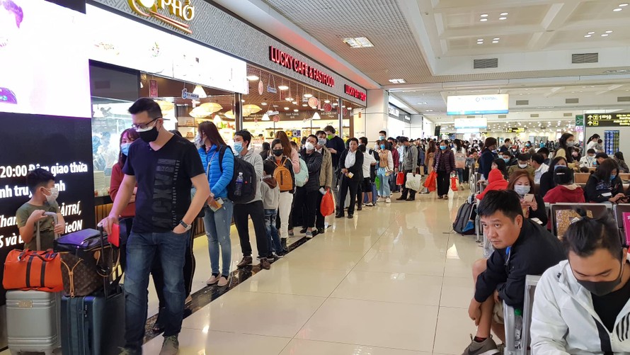 Hành khách đeo khẩu trang sếp hàng làm thủ tục tại sân bay Nội Bài. Ảnh: M.Đ
