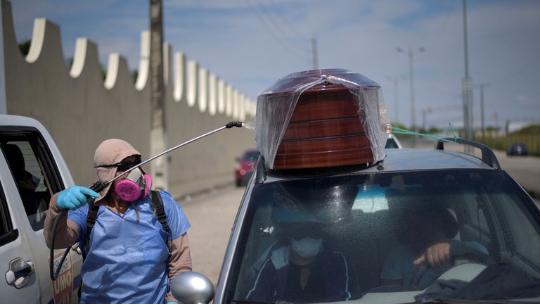 Một công nhân phun thuốc khử trùng lên một chiếc xe chở quan tài đang xếp hàng để vào nghĩa trang thành phố Guayaquil ngày 2/4. Ảnh: Reuters 