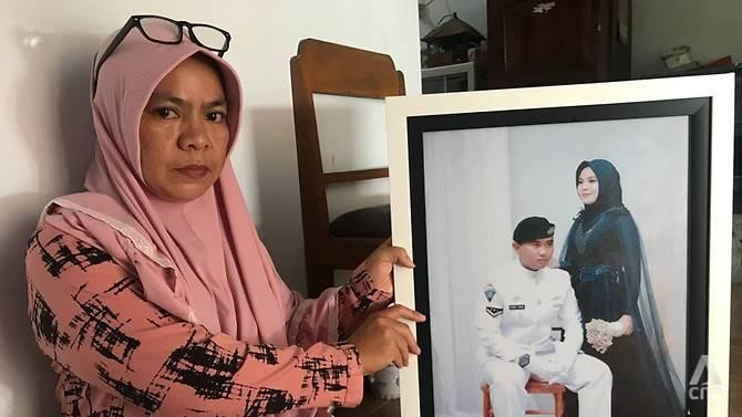 Bà Yayak Dwi Ernawati cầm ảnh cưới của con gái và con rể - thủy thủ tàu ngầm KRI Nanggala-402. Ảnh: CNA