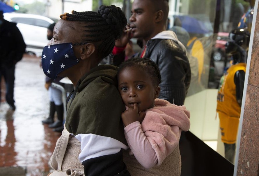 Một phụ nữ đeo khẩu trang địu con đi trên phố ở Pretoria (Nam Phi) ngày 27/11. Ảnh: AP