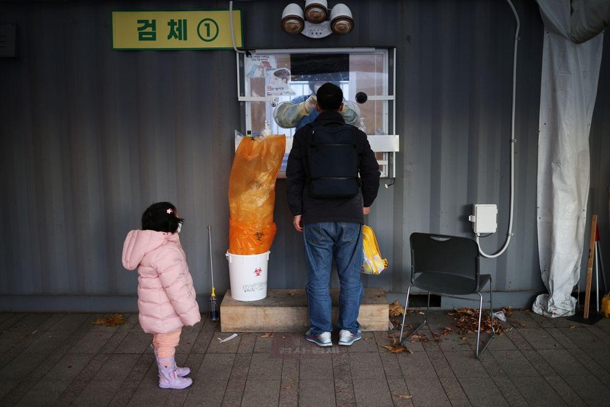 Một bé gái chờ bố lấy mẫu xét nghiệm ở Seoul (Hàn Quốc). Ảnh: Reuters