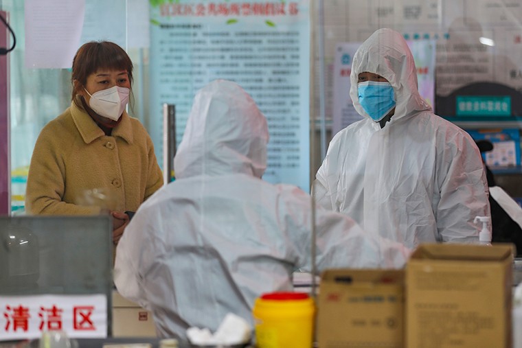 Nhân viên y tế tại một trạm y tế nói chuyện với một phụ nữ nghi nhiễm coronavirus ở Vũ Hán ngày 27/1. Ảnh: AP.