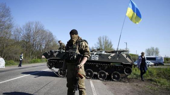 Một lính Ukraine đứng trước xe tăng ở trạm kiểm soát tại làng Malinivka, Slaviansk, đông Ukraine 