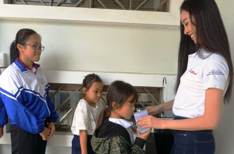 Á hậu Nguyễn Thị Thúy An rót nước cho các trẻ em uống nước tại chương trình Ký túc xá 115, tại xã Ea Dah, huyện Krông Năng, tỉnh Đắk Lắk.