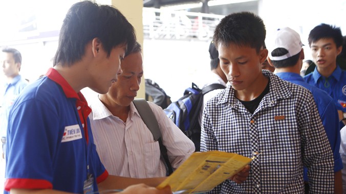 Sĩ tử lên Hà Nội dự thi được thanh niên tình nguyện hướng dẫn tại bến xe phía Nam. Ảnh: Như Ý
