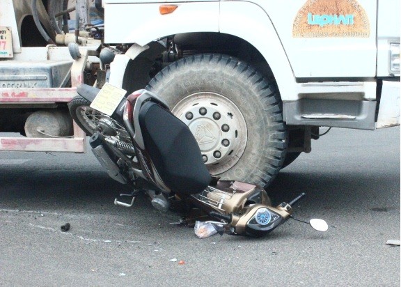 Sau cú va chạm phần đầu chiếc xe máy bị bẹp dí dưới bánh xe bồn.