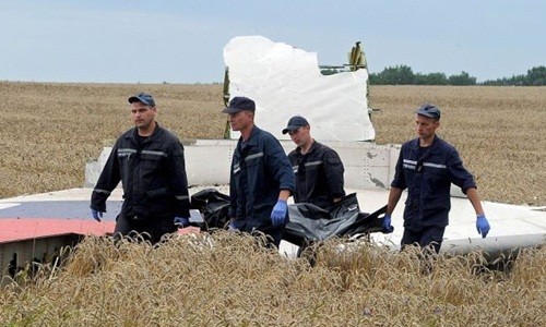 Nhóm cứu hộ đưa thi thể nạn nhân thảm họa MH17 rời khỏi hiện trường tháng 7/2014, bên cạnh là một mảnh vỡ máy bay. Ảnh: AFP.